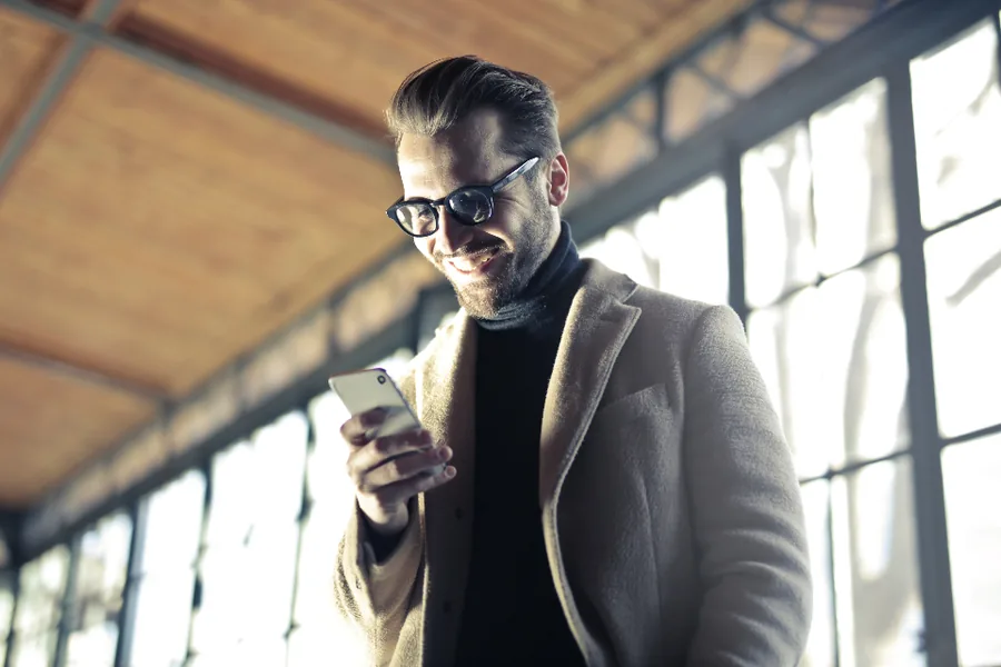 Person smiling at their phone by a window
